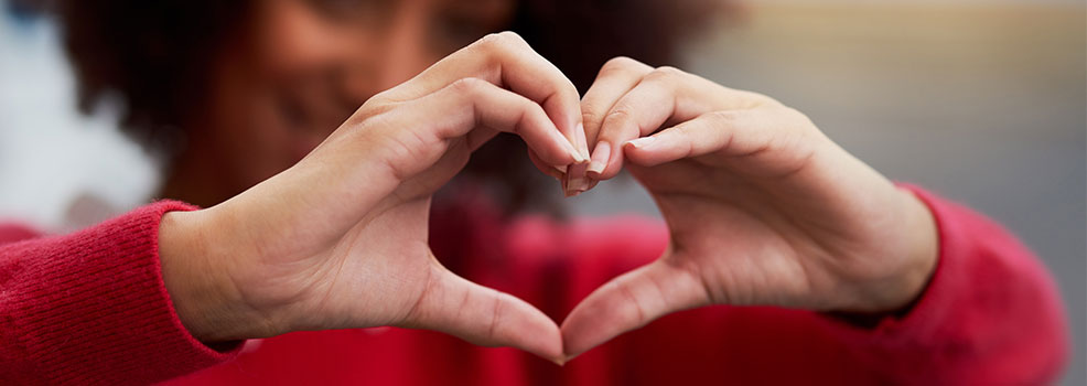 Mujer dibujando un corazón con sus manos