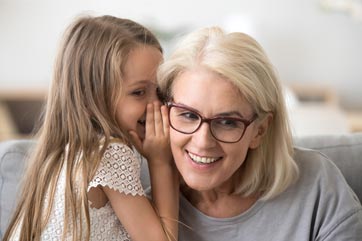 Granddaughter whispering to her grandmother.