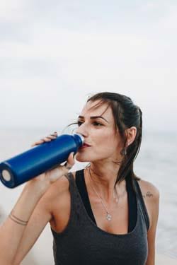 mujer bebiendo agua de la botella de agua reciclable