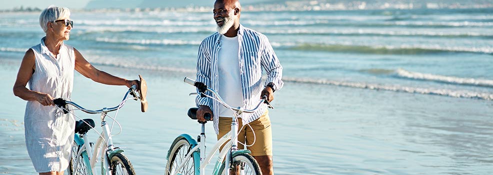 Pareja mayor andando en bicicleta en la playa