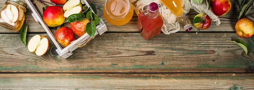 Apple cider vinegar and fresh apples on wooden table