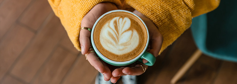 hands holding cappuccino with latte art